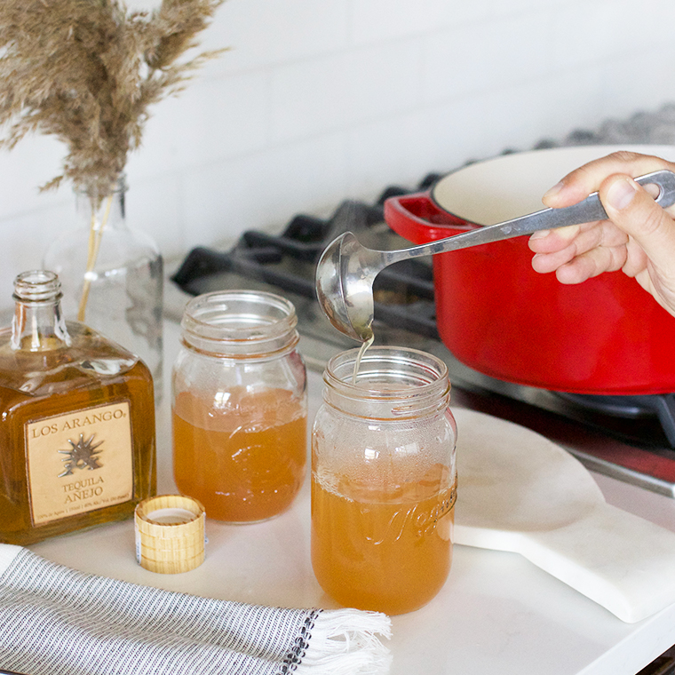 Mason jar and hot cider being poured into it with ladle